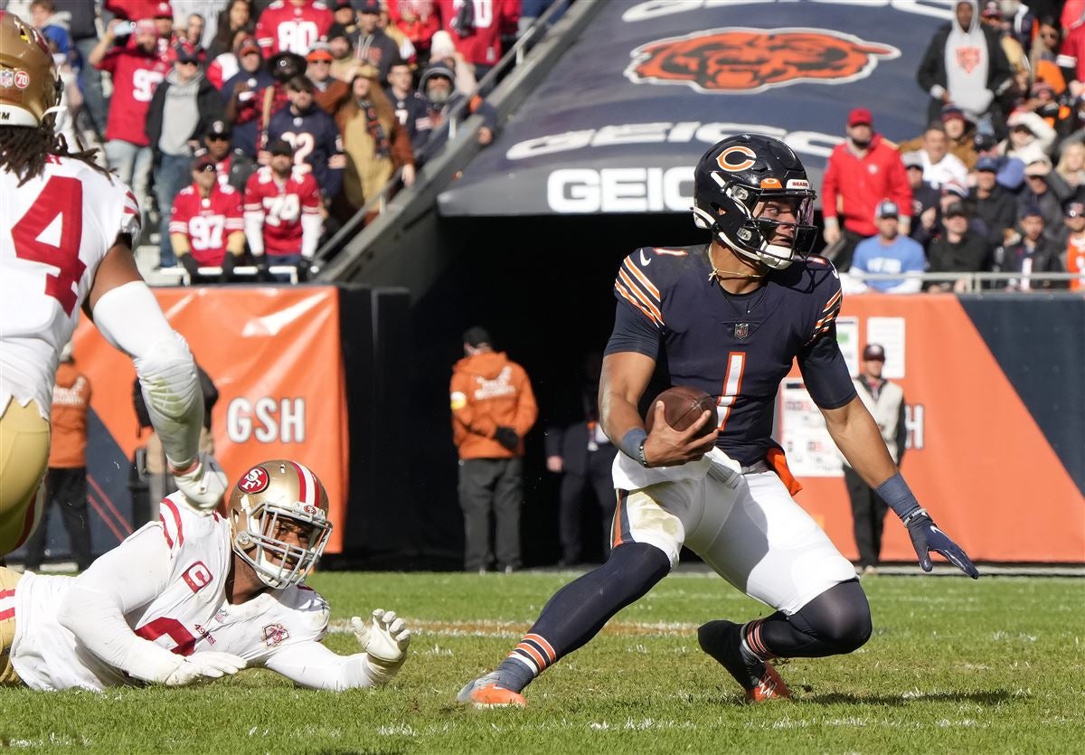 Chicago Bears' Justin Fields shuffle passes while being pressured