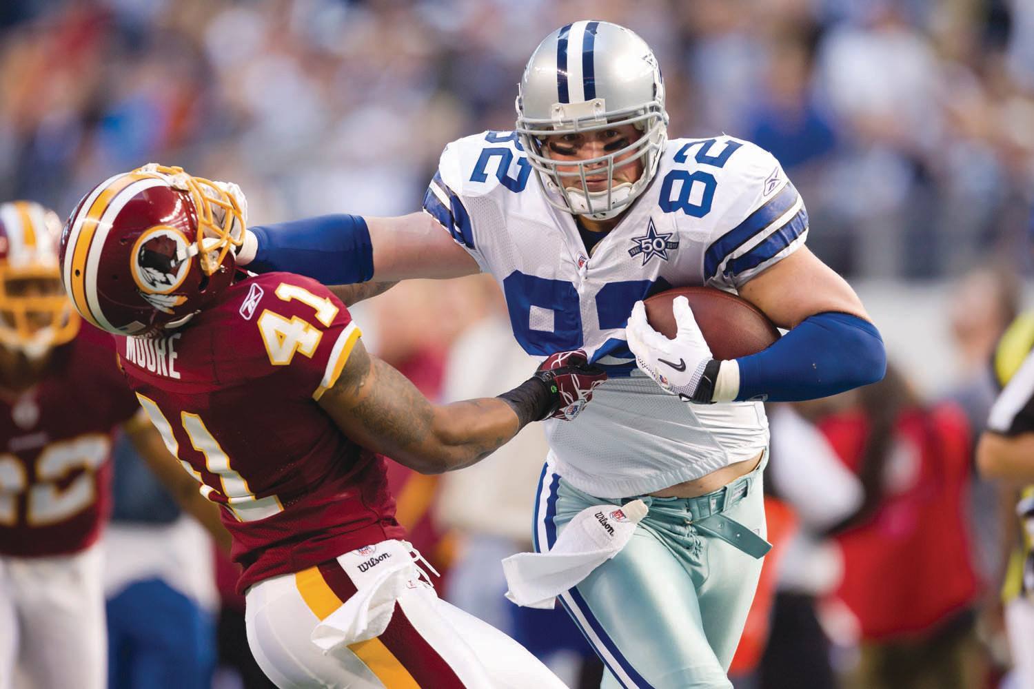 Dallas Cowboys tight end Jason Witten (82) stiff arms Washington Redskins  strong safety DeJon Gomes (24) on a 4-yard pass play in the third quarter  at Cowboys Stadium in Arlington, Texas, on Thanksgiving Day, Thursday,  November 22, 2012. The